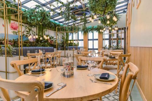 a restaurant with wooden tables and chairs and plants at Faranda Collection Barranquilla, a member of Radisson Individuals in Barranquilla