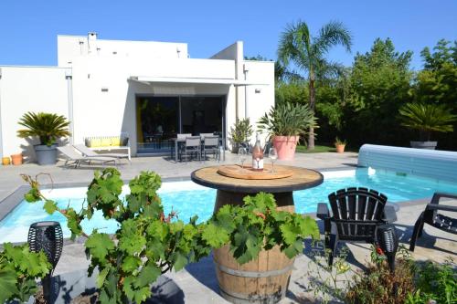 un patio avec une table et des chaises à côté d'une piscine dans l'établissement Villa de standing Piscine privée à 15 min des plages 8VB11, à Perpignan
