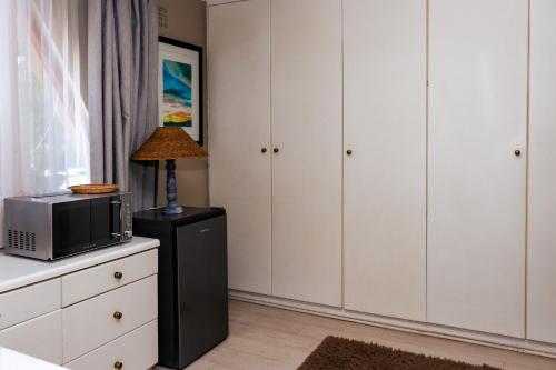 a room with white cabinets and a microwave and a tv at STAY In TEHAMA in Cape Town