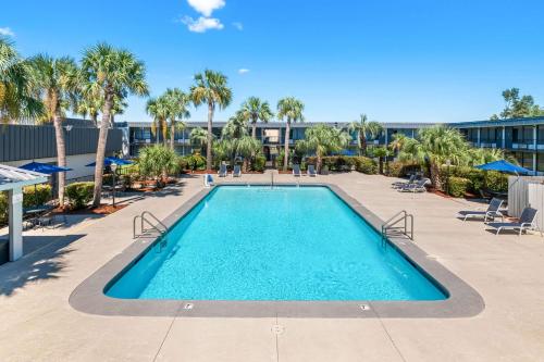 a swimming pool at a resort with palm trees at Quality Inn Slidell I-10 in Slidell