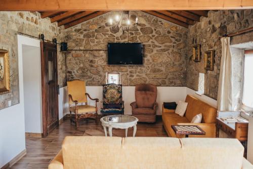 a living room with a couch and chairs and a tv at Casa da Carvalha in Vale de Cambra
