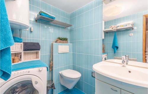 a blue tiled bathroom with a washing machine and a sink at Cozy Home In Miholascica With Wifi in Miholašćica