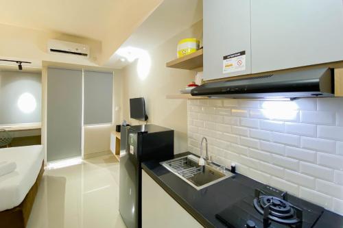 ブカシにあるHomey and Well Furnished Studio Gateway Park LRT City Jatibening Apartment By Travelioのシンクとコンロのある小さなキッチン