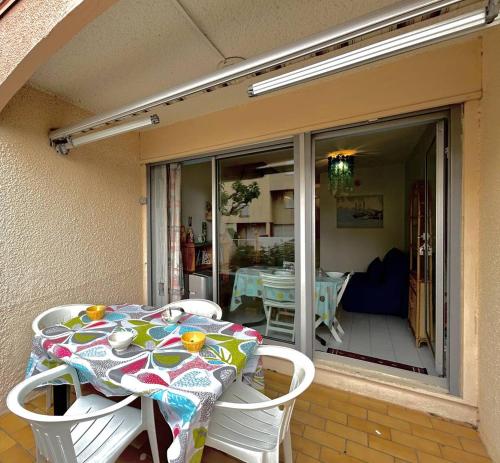 une table et des chaises assises sur une terrasse avec une fenêtre en verre dans l'établissement Agréable 3 pièces en Duplex - terrasse - parking privé - 5POPL10, au Barcarès