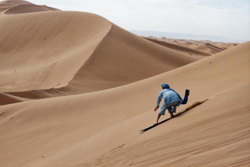 a man walking up a sand dune in the desert at Merzouga Glamping With AC in Merzouga