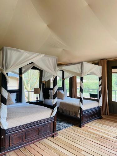 a bedroom with two beds and a canopy at Mara Sweet Acacia Lodge in Talek