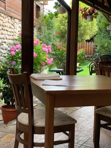 a wooden table and chairs on a patio with flowers at Kralev Dvor Hotel in Bansko