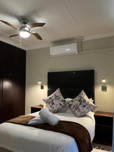 a bedroom with a bed with pillows and a ceiling fan at Turn and slip in Bloemfontein