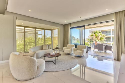a living room with chairs and tables and windows at Waterfront Village in Cape Town
