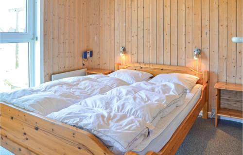 a large wooden bed with white sheets in a room at Stunning Home In Thisted With Sauna in Klitmøller