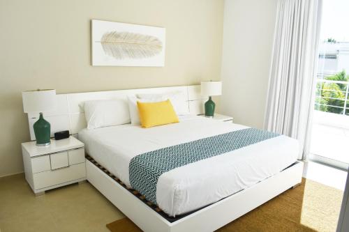 a white bedroom with a white bed and a window at Ka' Romana Residences in El Soco