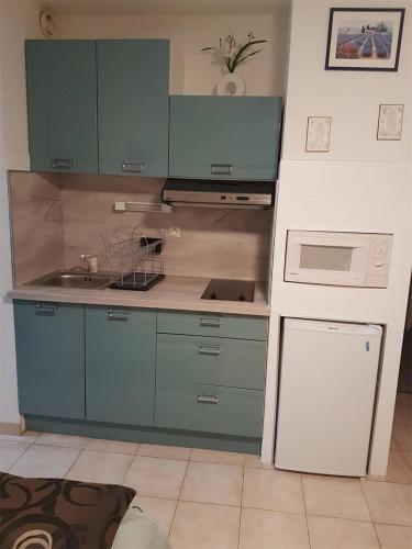 une cuisine avec des armoires bleues et un appareil blanc dans l'établissement Deux pièce vue Mer et Port 4PP2B32, au Barcarès