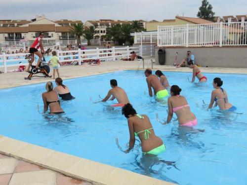 un groupe de personnes dans une piscine dans l'établissement Appartement équipé pour 4 personnes avec piscine - 4CARA8, au Barcarès