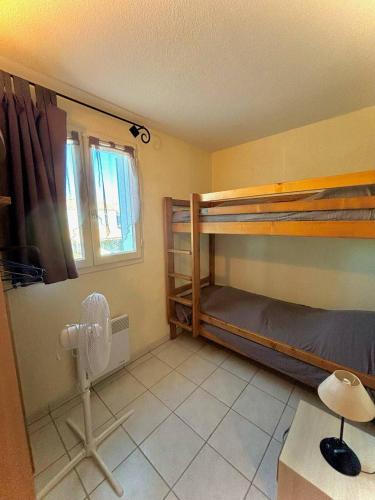 Cette chambre comprend 2 lits superposés et un ventilateur. dans l'établissement Agréable maisonnette piscine collective 4IDP3031, au Barcarès
