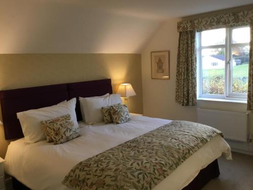 ein Schlafzimmer mit einem großen Bett mit Kissen und einem Fenster in der Unterkunft Coach House Wroxham Holiday Cottage in Wroxham