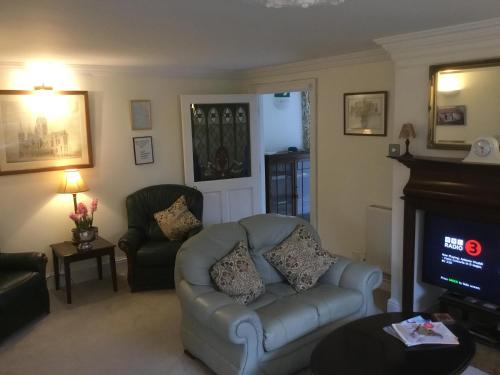 ein Wohnzimmer mit Sofa und Fernseher in der Unterkunft Coach House Wroxham Holiday Cottage in Wroxham
