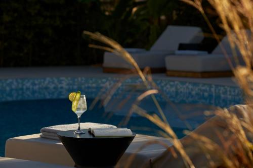 a glass of wine sitting on a table next to a pool at Poesia Suites in Lakithra