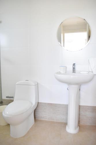 a white bathroom with a toilet and a sink at Ka' Romana Residences in El Soco