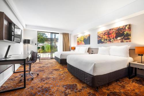 a hotel room with two beds and a desk at Crowne Plaza Alice Springs Lasseters by IHG in Alice Springs