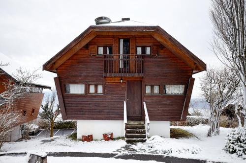 a wooden house with a balcony in the snow at chalet haute-savoie in Thollon