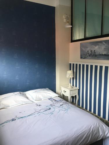 une chambre avec un grand lit avec un mur bleu dans l'établissement Sans Adieu, à Wimereux