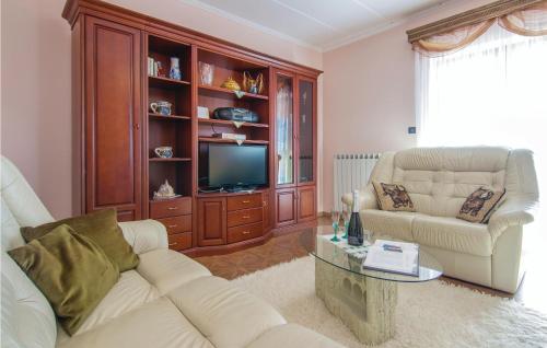 a living room with two white couches and a tv at Holiday Home Livaki Iv in Muntrilj