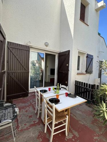 une table blanche et des chaises sur une terrasse dans l'établissement Appartement dans un secteur calme proche de la plage 4MAR3R4, au Barcarès