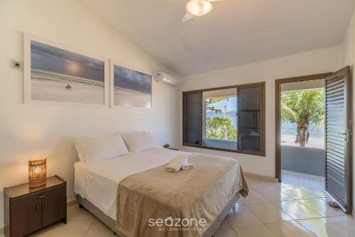 a bedroom with a bed and a view of the beach at Casa 6Q pé na areia em Bombinhas ABM0101 in Zimbros