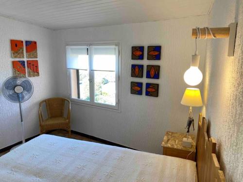 une chambre avec un lit avec une lampe et une fenêtre dans l'établissement Marseillan plage 5pers proche plage climatisé, à Marseillan