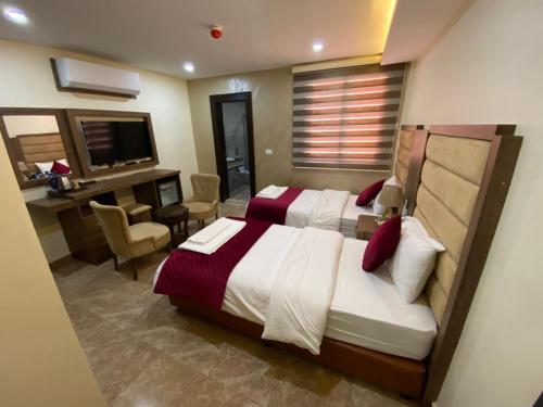 a bedroom with a bed and a desk and a television at Sunset Hotel in Wadi Musa