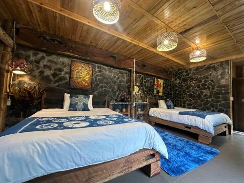 a bedroom with two beds and a stone wall at Ha Giang Xanh Retreat - Trekking, Tour, Motorbike Rental in Ha Giang