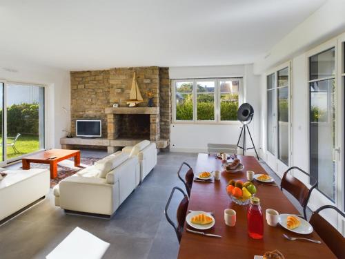 un salon avec une table et des chaises et une cheminée dans l'établissement -OZARIO- Magnifique maison au Cabellou, à Concarneau