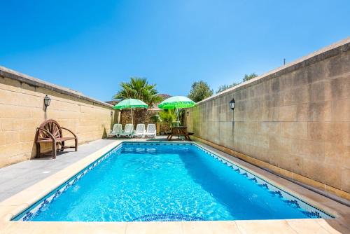 a swimming pool with blue water in front of a wall at 4 Bedroom Holiday Home with Private Pool in Għarb