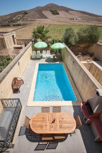 a swimming pool with tables and umbrellas on a patio at 4 Bedroom Holiday Home with Private Pool in Għarb