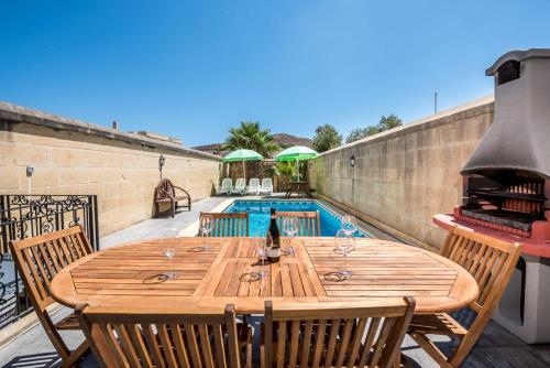 a wooden table and chairs on a patio with a pool at 4 Bedroom Holiday Home with Private Pool in Għarb