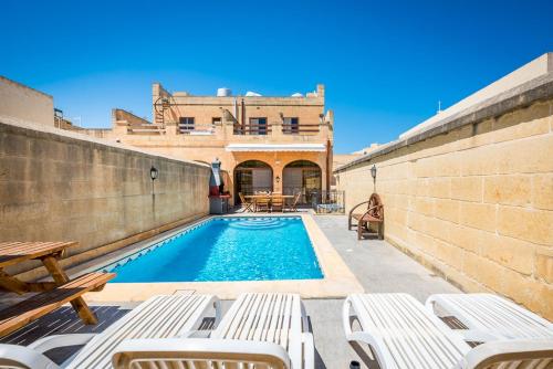 a swimming pool with chairs and a house at 4 Bedroom Holiday Home with Private Pool in Għarb