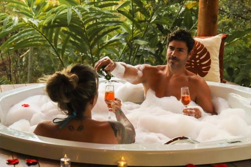 a man and a woman in a bath tub with champagne at Vila Verde in Palmeiras