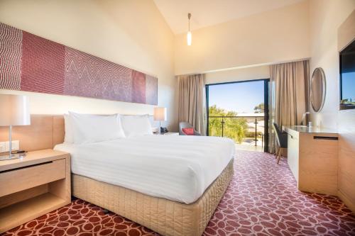 a hotel room with a large bed and a balcony at Crowne Plaza Alice Springs Lasseters by IHG in Alice Springs