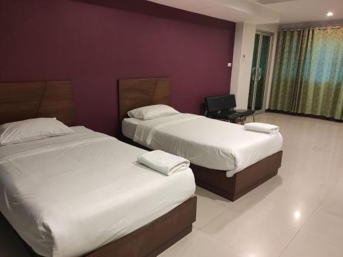 a hotel room with two beds and a chair at Baan Manthana Hotel, Hua Hin in Hua Hin