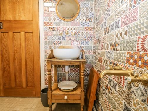 a bathroom with a sink and a mirror on a tiled wall at The Bike Shed in Romsey
