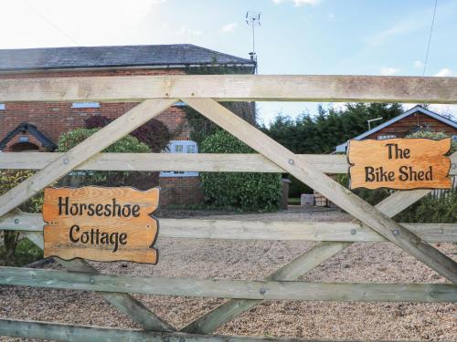 a wooden gate with two wooden signs on it at The Bike Shed in Romsey