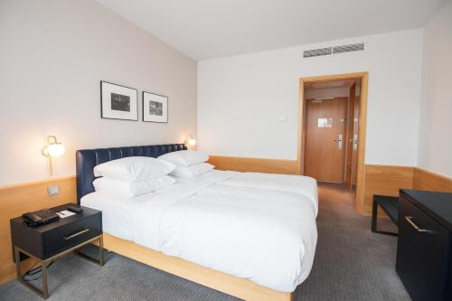 a bedroom with a large white bed and a desk at K+K Hotel Fenix in Prague