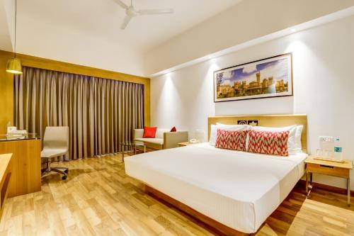 a hotel room with a bed and a desk at Lemon Tree Hotel Electronics City in Bengaluru
