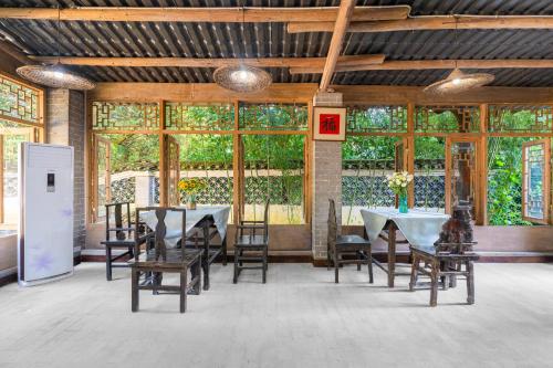a dining room with tables and chairs and windows at Leisure Courtyard Hotel Yangshuo in Yangshuo