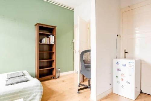 a room with a chair and a refrigerator at Cozy private room in shared apartment, close to beach and city center in The Hague