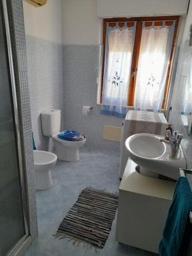 a bathroom with a toilet and a sink and a toilet istg at Villa S'Oliariu in Martis
