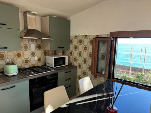 a kitchen with a stove and a microwave and a window at Hotel Lora RDA Luxury in Bordighera