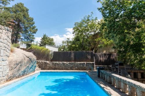 a swimming pool in a yard with a stone wall at Espectacular vista en la fuenfria in Cercedilla