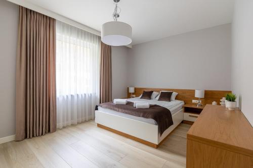 a bedroom with a bed and a desk and a window at Skarbka House - luksusowy dom całoroczny z jacuzzi koło Bałtowa in Bałtów