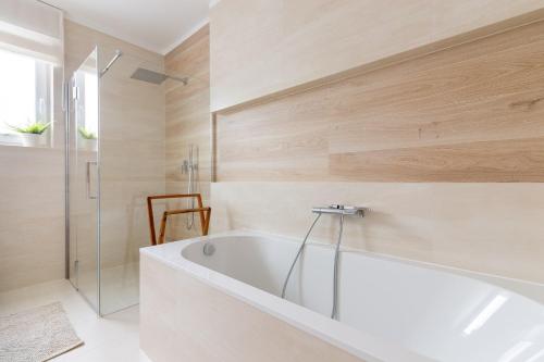 a white bath tub in a bathroom with wooden walls at Skarbka House - luksusowy dom całoroczny z jacuzzi koło Bałtowa in Bałtów